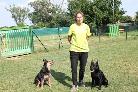 Melanie Zoe Chiavarotti in piedi sul campo con due cani neri seduti