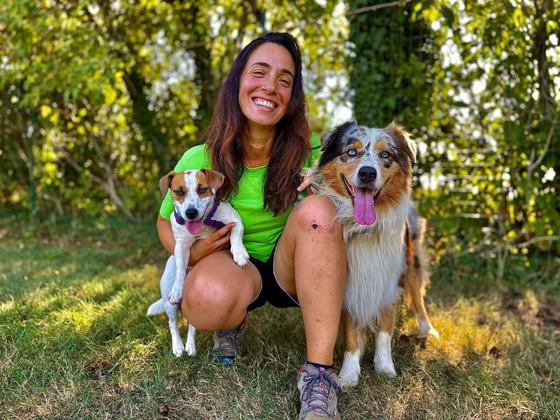 Sara Roberti sorridente con in braccio un jack russell, accanto a un pastore australiano
